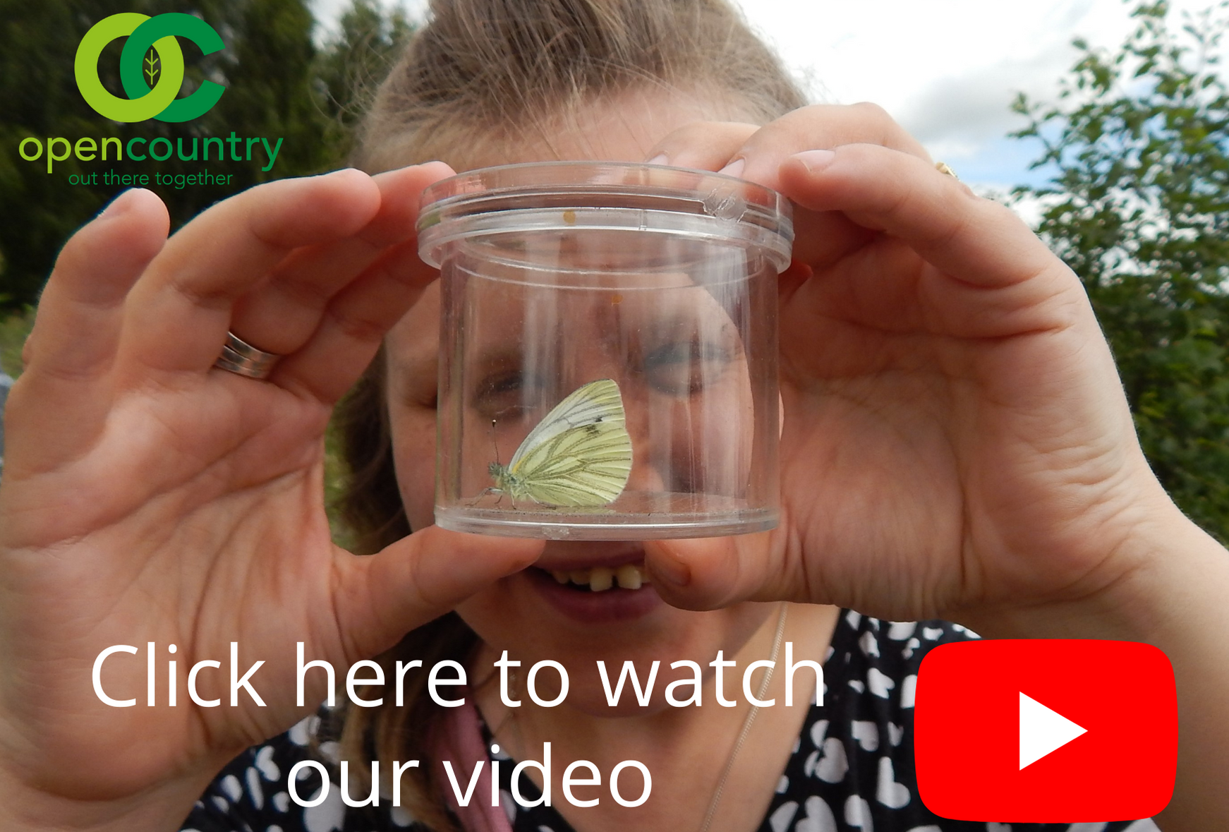 An Open Country member examines a butterfly up close in a specimen pot