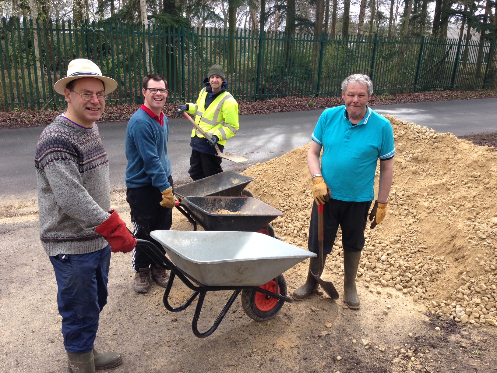 The group doing path work, standing next to wheelbarrows with shovels.