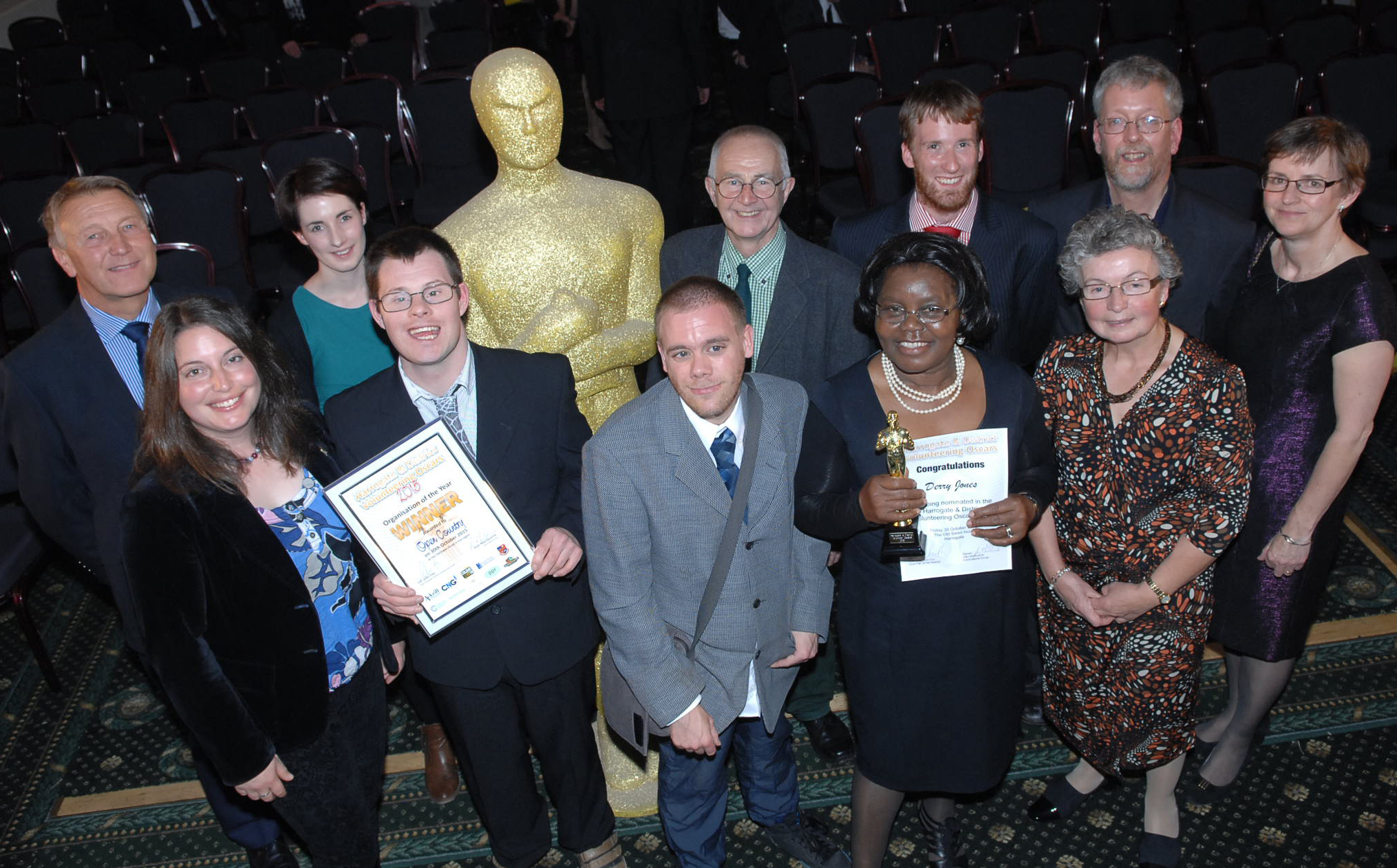 A group of people smartly dressed holding certificates and awards.