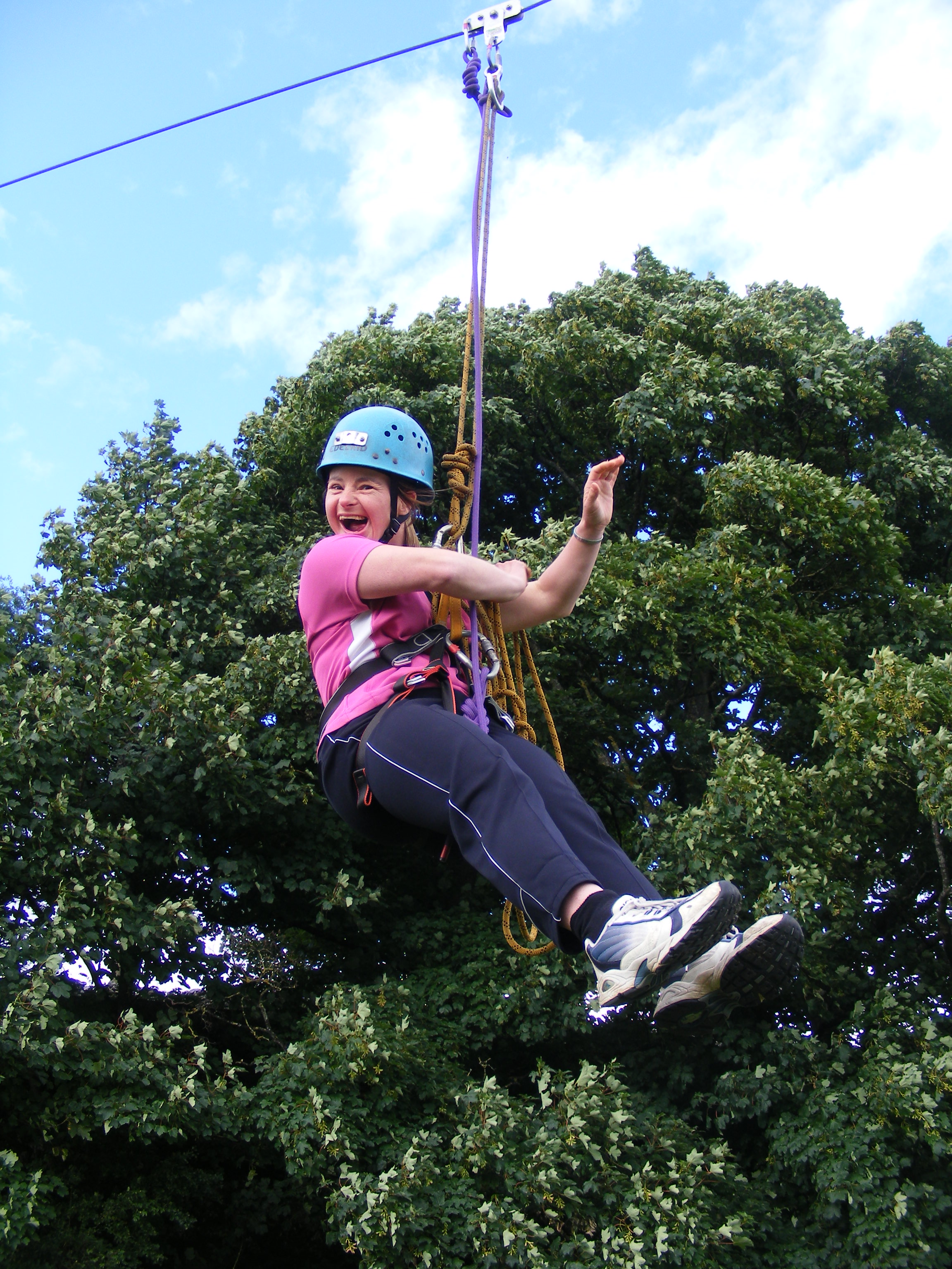 A woman on a zip wire with trees behind
