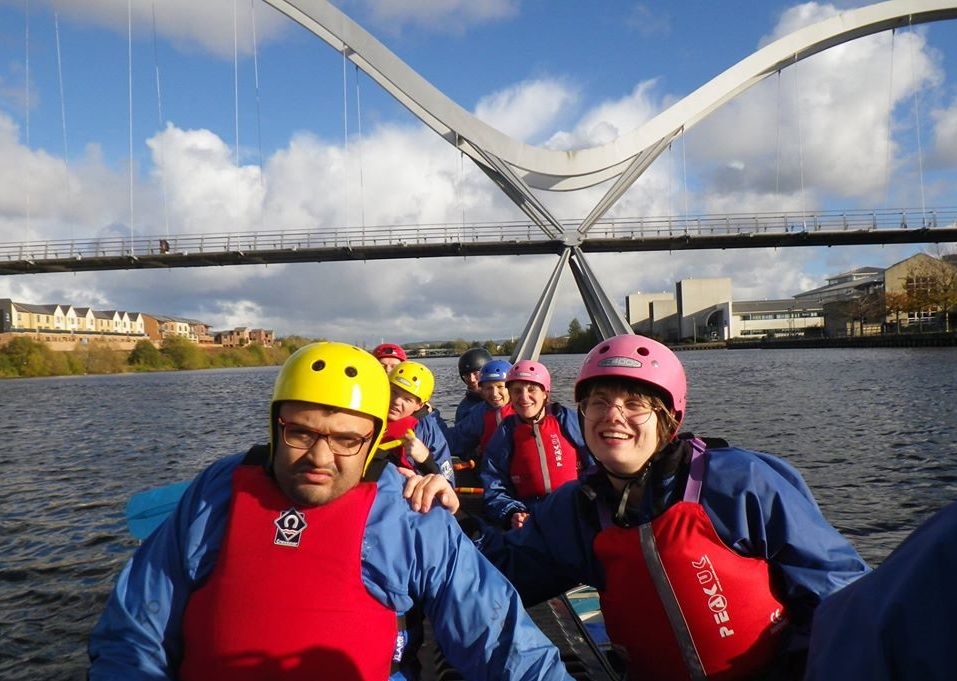 People on a bell boat with helmets and life jackets on.