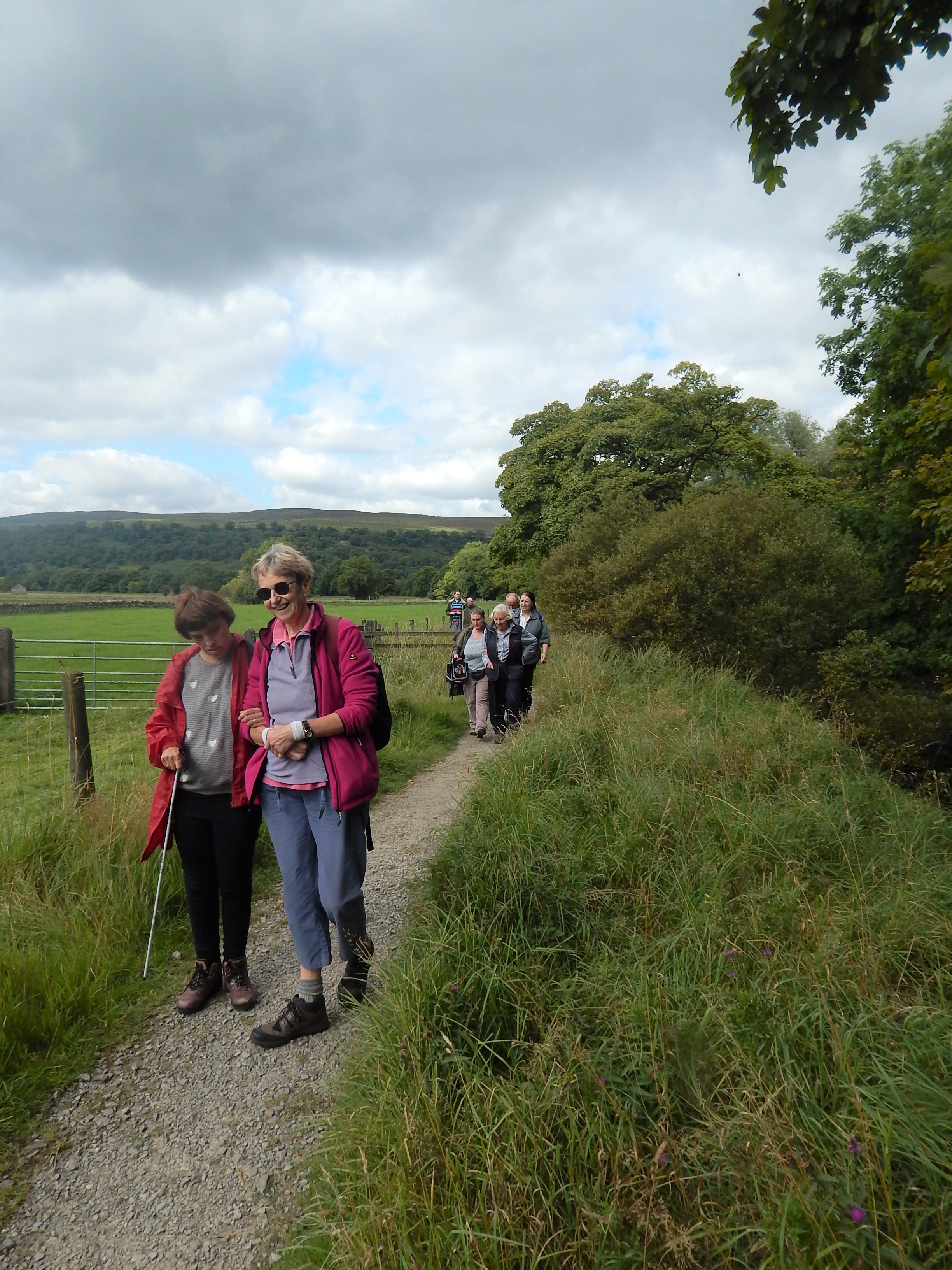 A woman guiding another woman, with trees and hills in the background