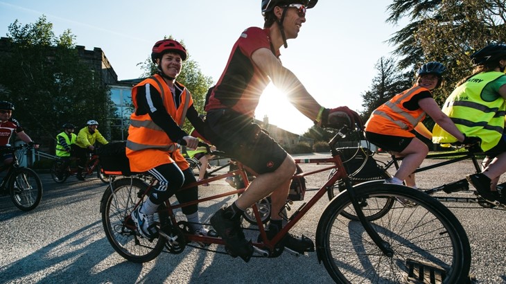 Tandem riders back lit by a sunburst