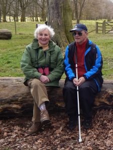 Volunteer Dottie and Mike sitting together on a log