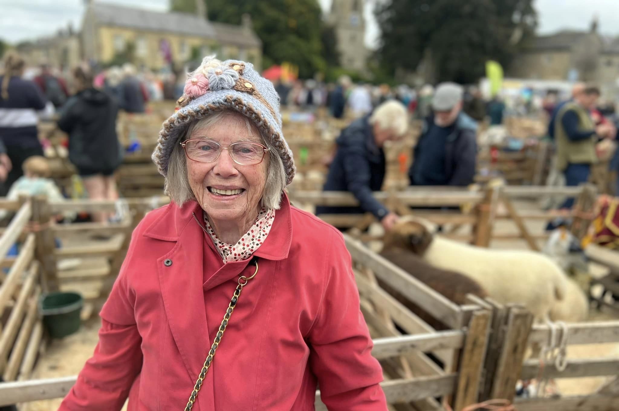 Masham Sheep Fair A smiling lady standing in front of a sheep pen