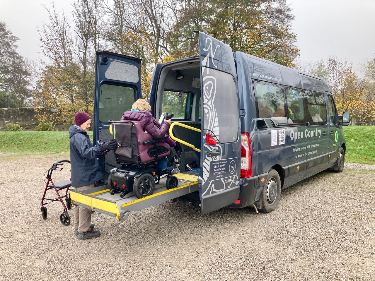 A woman in a wheelchair getting off a minibus on the rear lift