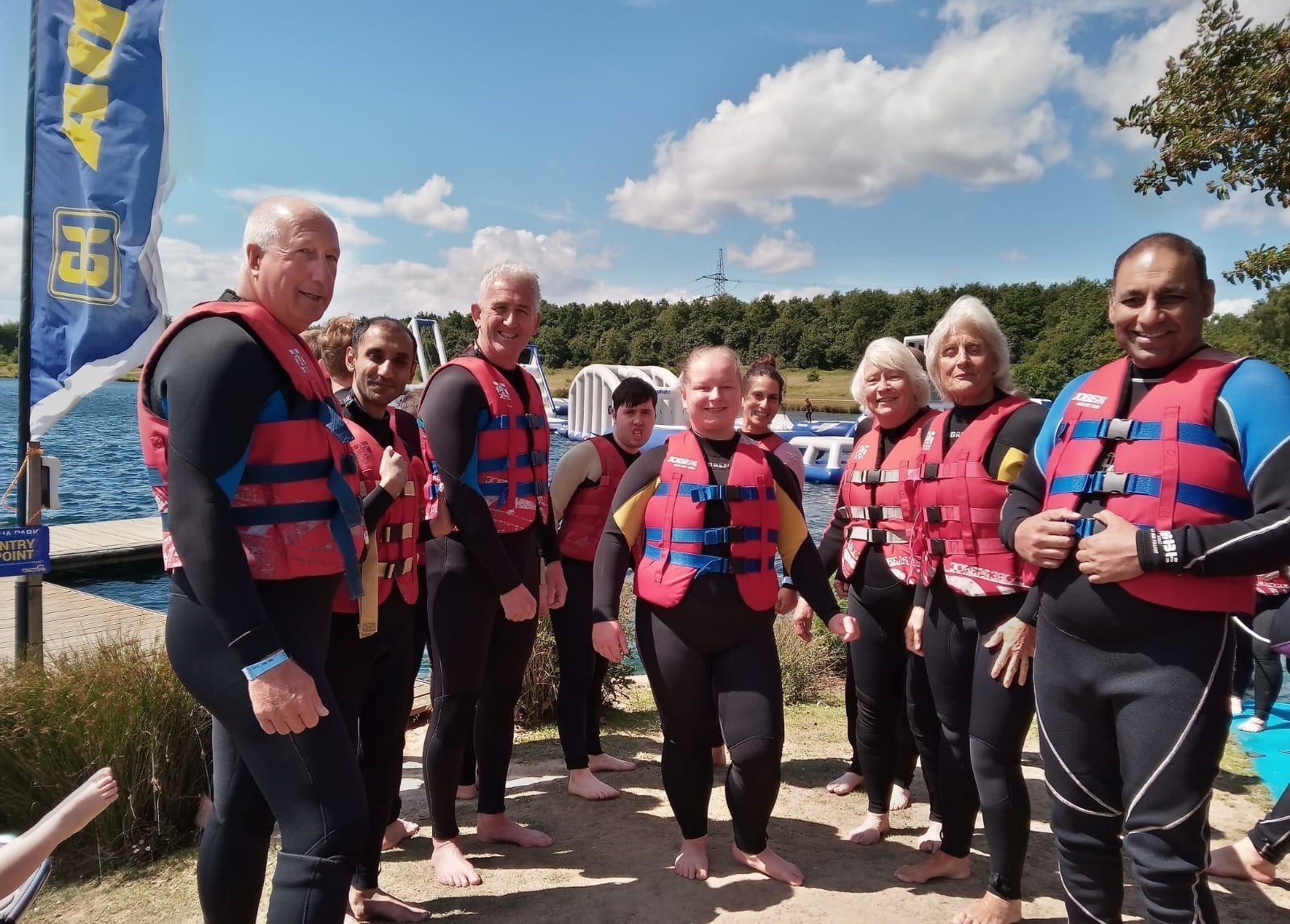 A group of people in life jackets standing in front of a lake