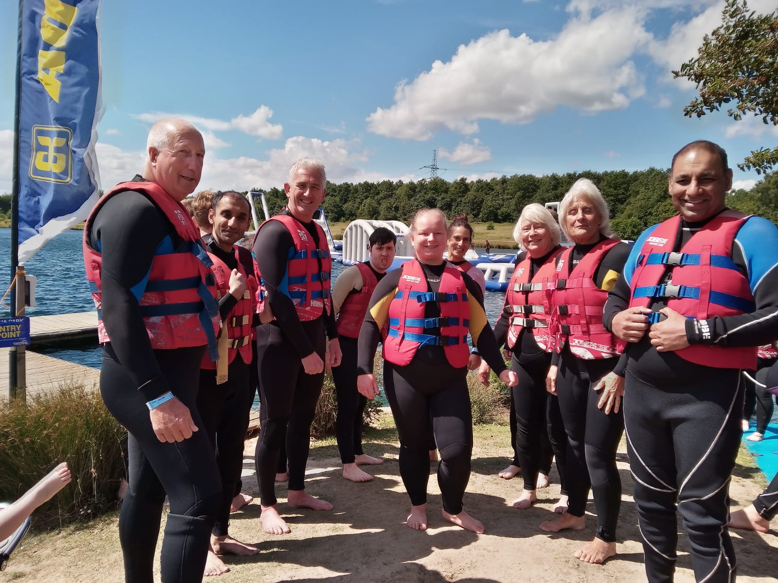 A group of people in life jackets standing in front of a lake